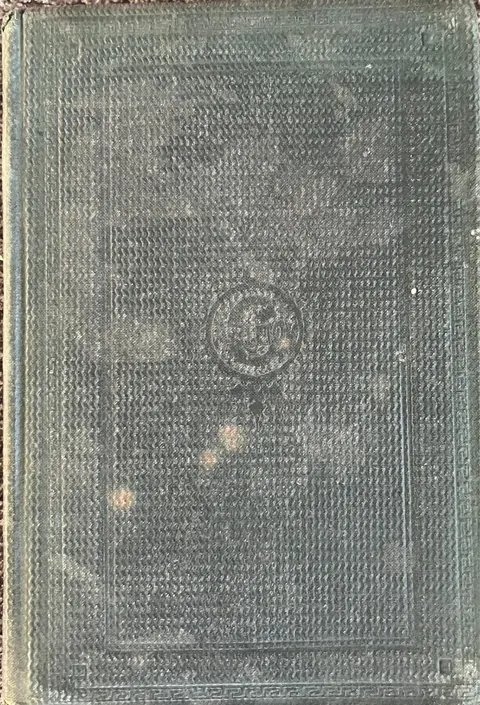 Dark green cloth book cover with a heavily textured waffle weave, a blind-stamped Greek key border and a central medallion, with no title or lettering visible